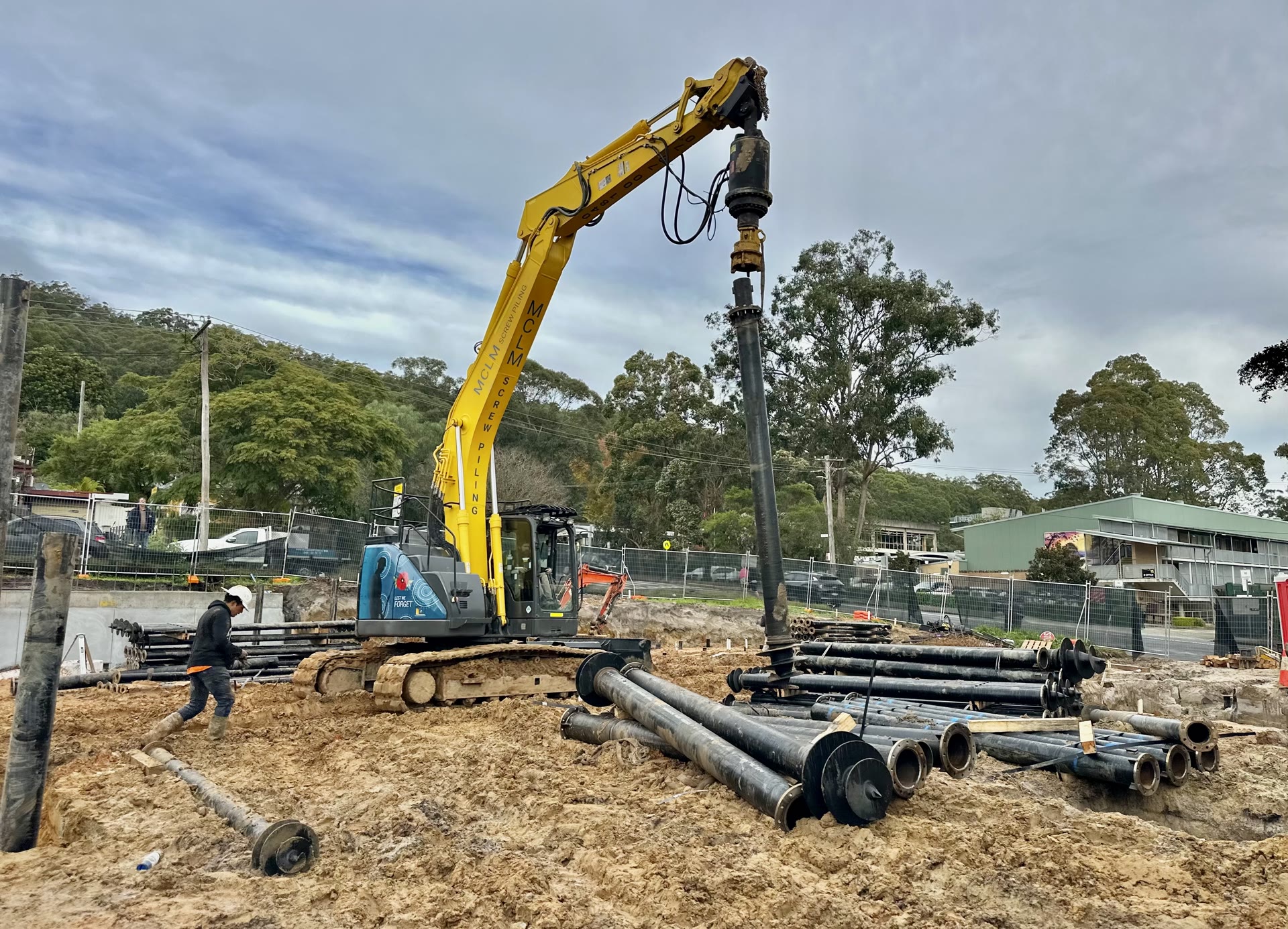 Compact piling equipment installing screw piles within an existing structure