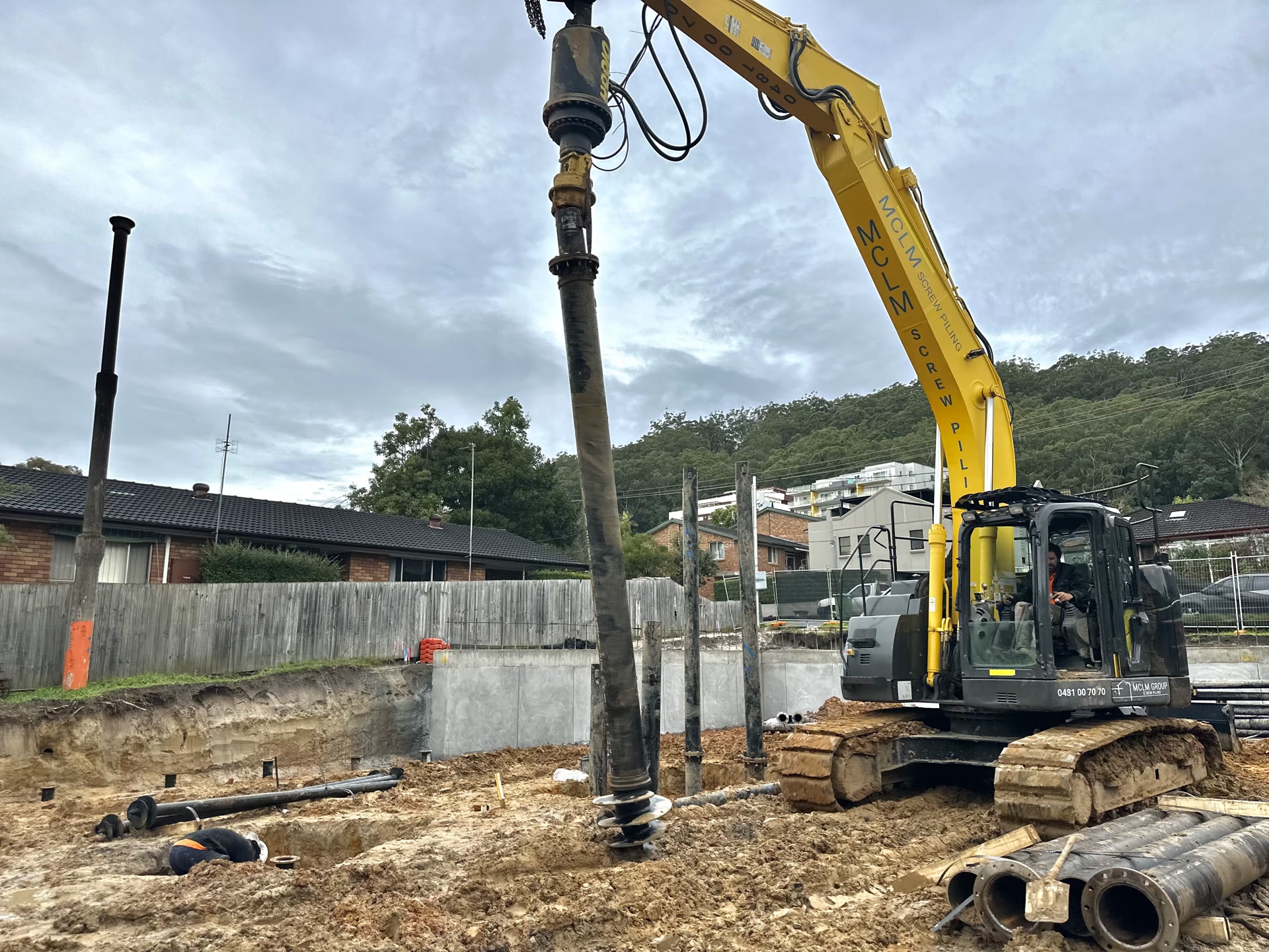 Screw pile installation beside a multi-storey commercial development